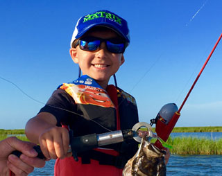 Small kid with a fishing rod and a smaller fish he caught