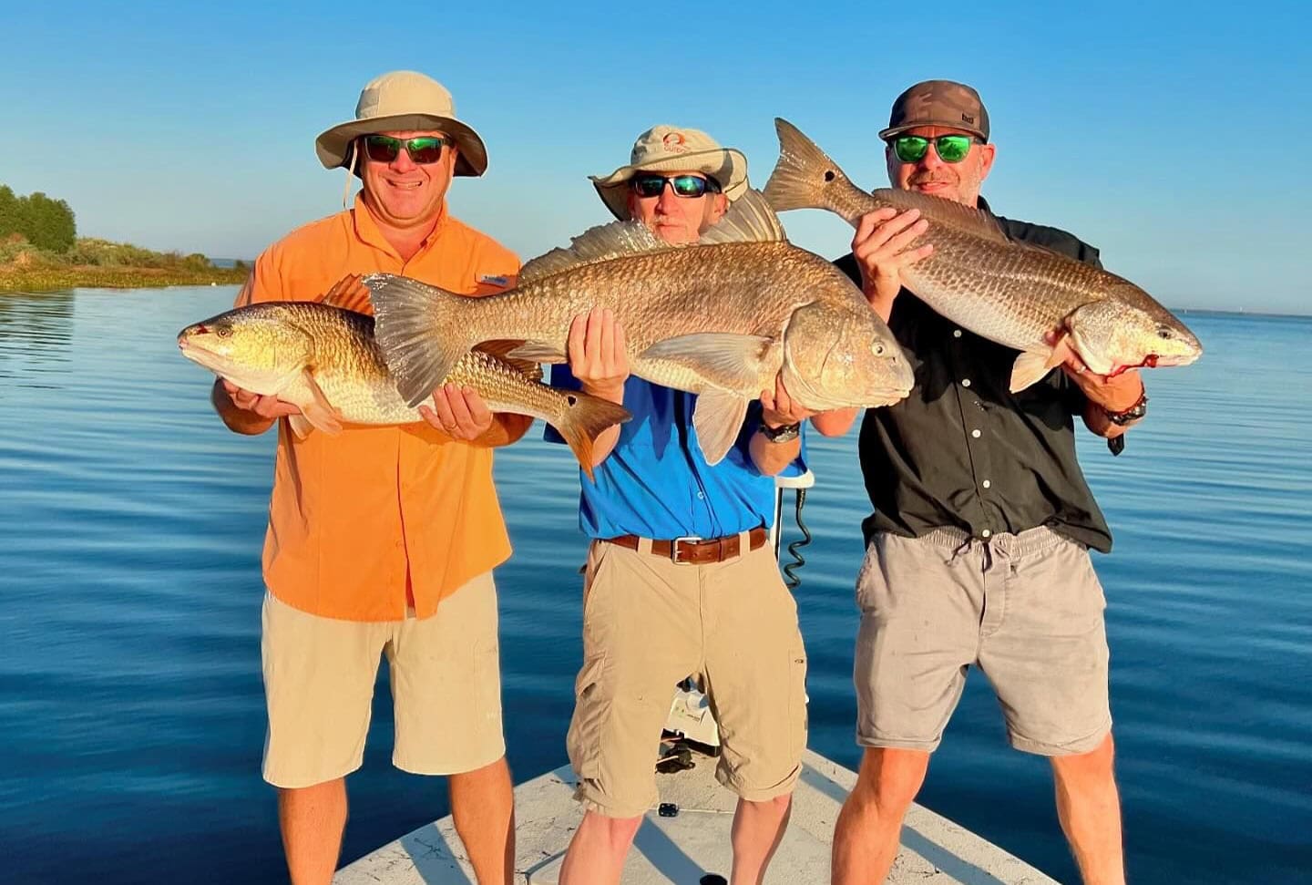 Three fishermen showing off their catches made with Whiskey Bayou Charters