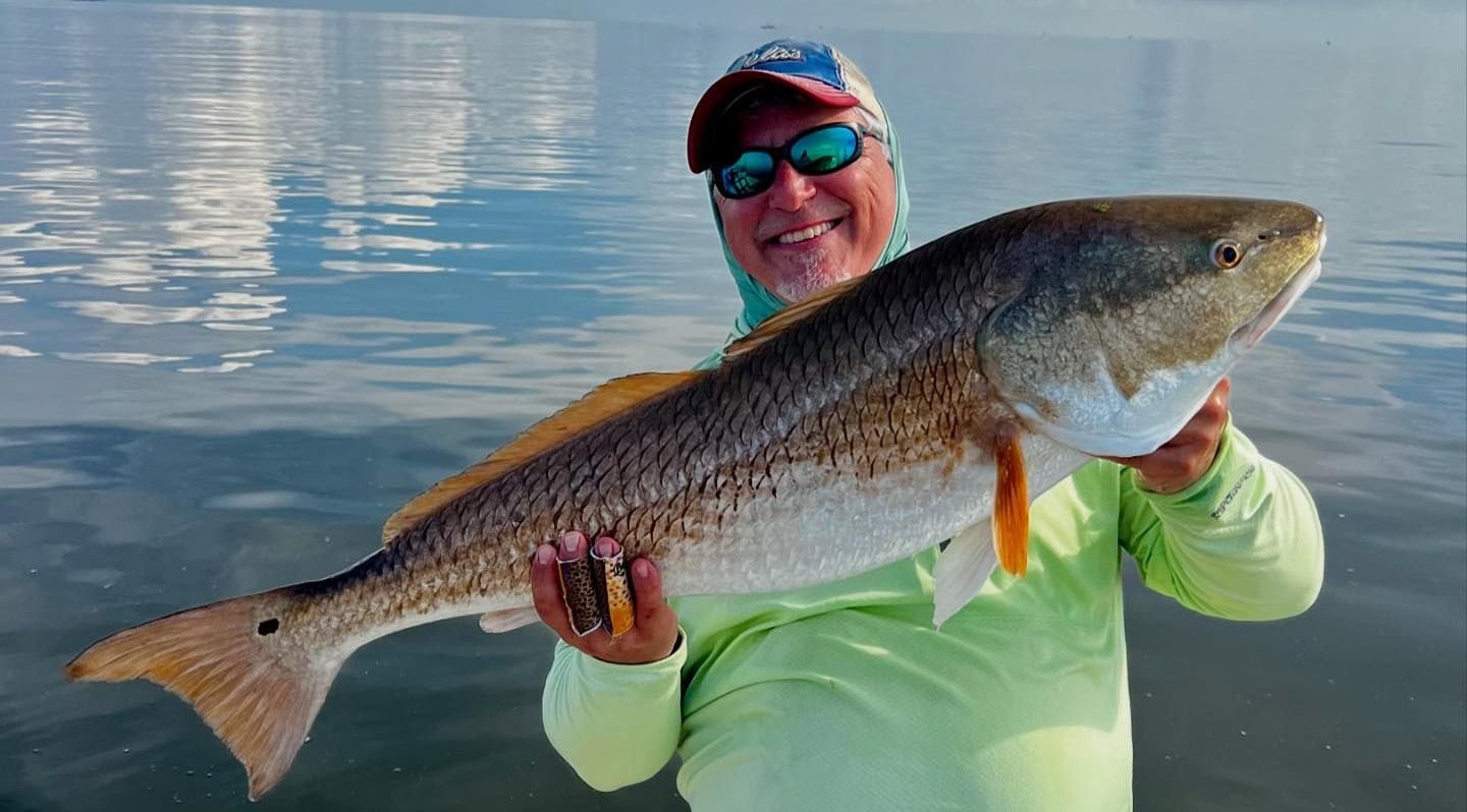 Man holding up a bull redfish he caught while on a fishing charter with Whiskey Bayou Charters in Venice, LA.