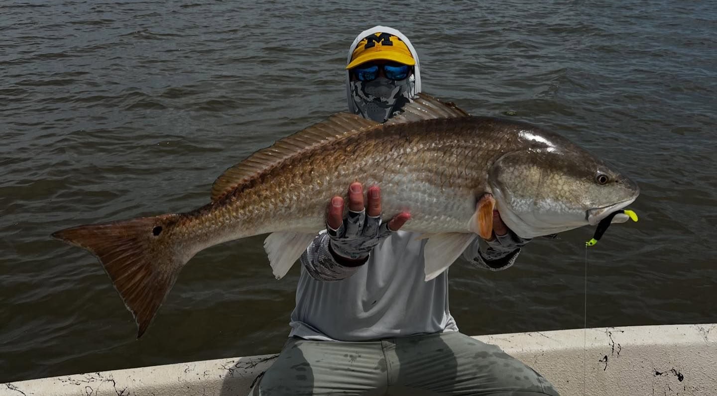 Man holding up a bull redfish he caught while on a fishing charter with Whiskey Bayou Charters in Venice, LA.