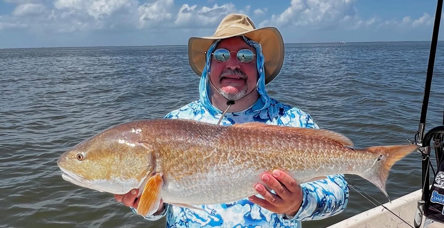 Man holding up a bull redfish he caught while on a fishing charter with Whiskey Bayou Charters in Venice, LA.