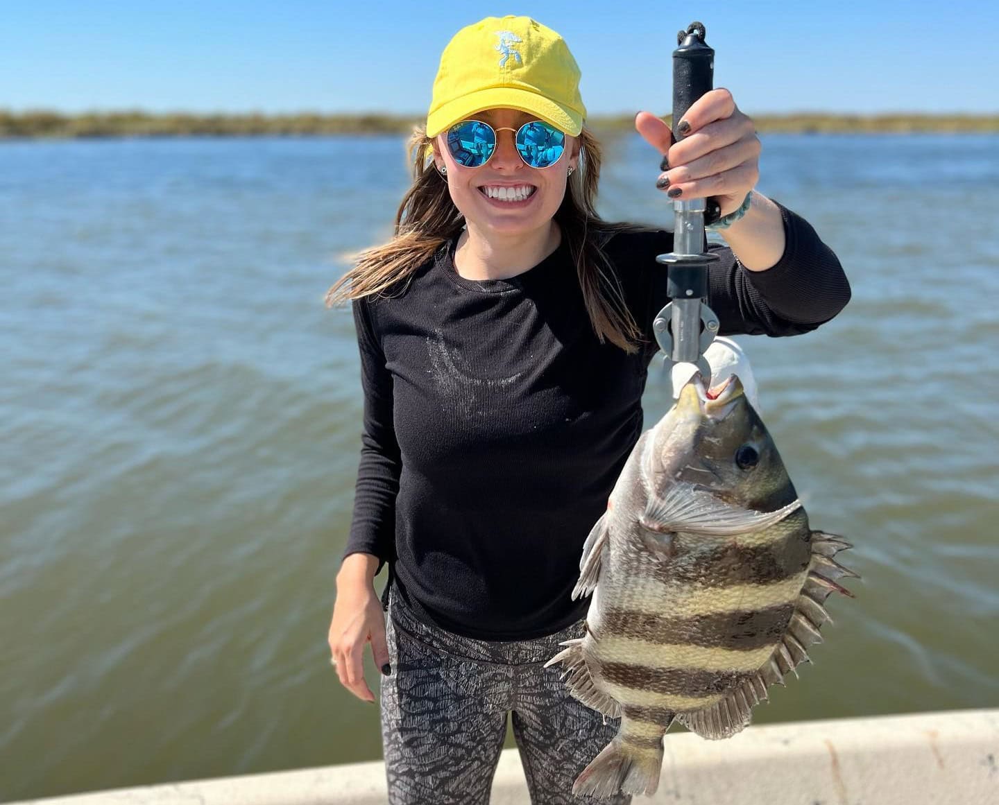 Woman holding up a sheepshead she caught while on a fishing charter in Delacroix.