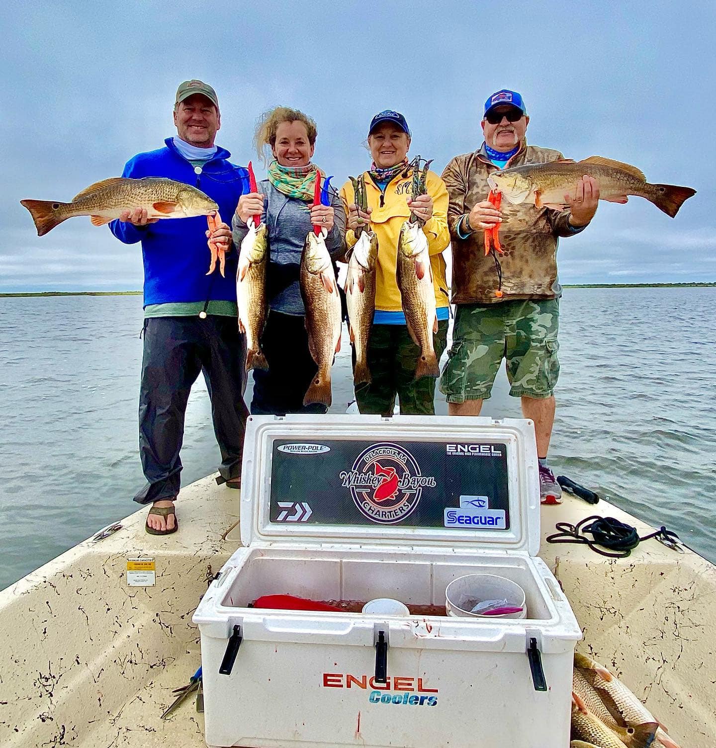 Friends on a fishing charter holding up the redfish they caught in the Delacroix marshes.