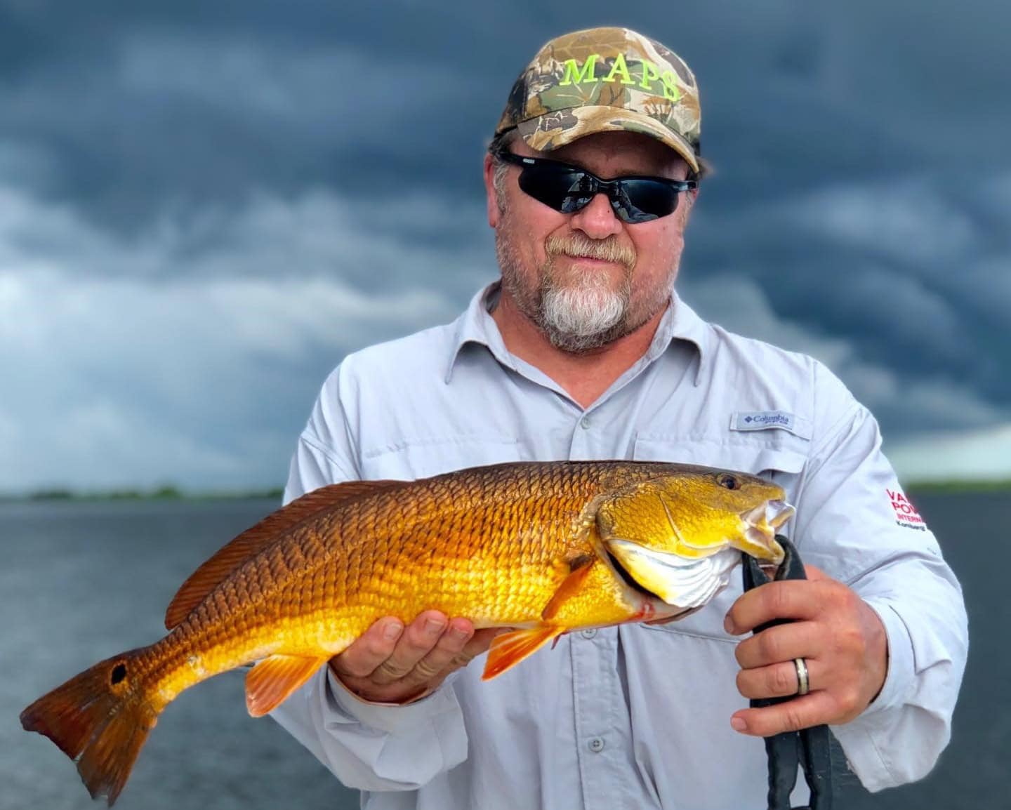 Man holding up a redfish he caught while on a fishing charter in Delacroix during the fall.