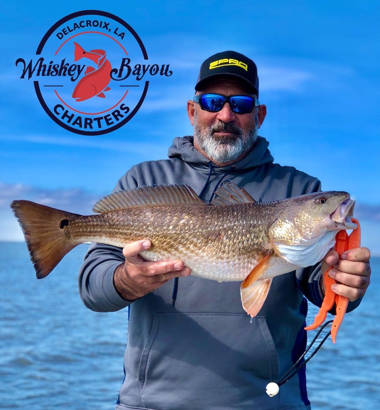 Fishing charter captain holding up a redfish he caught in Delacroix, LA.