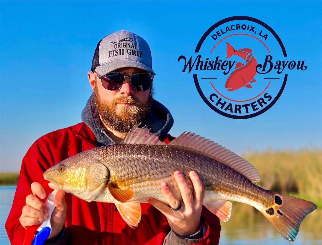 Man holding up a redfish he caught while on a fishing charter in Delacroix during the fall.