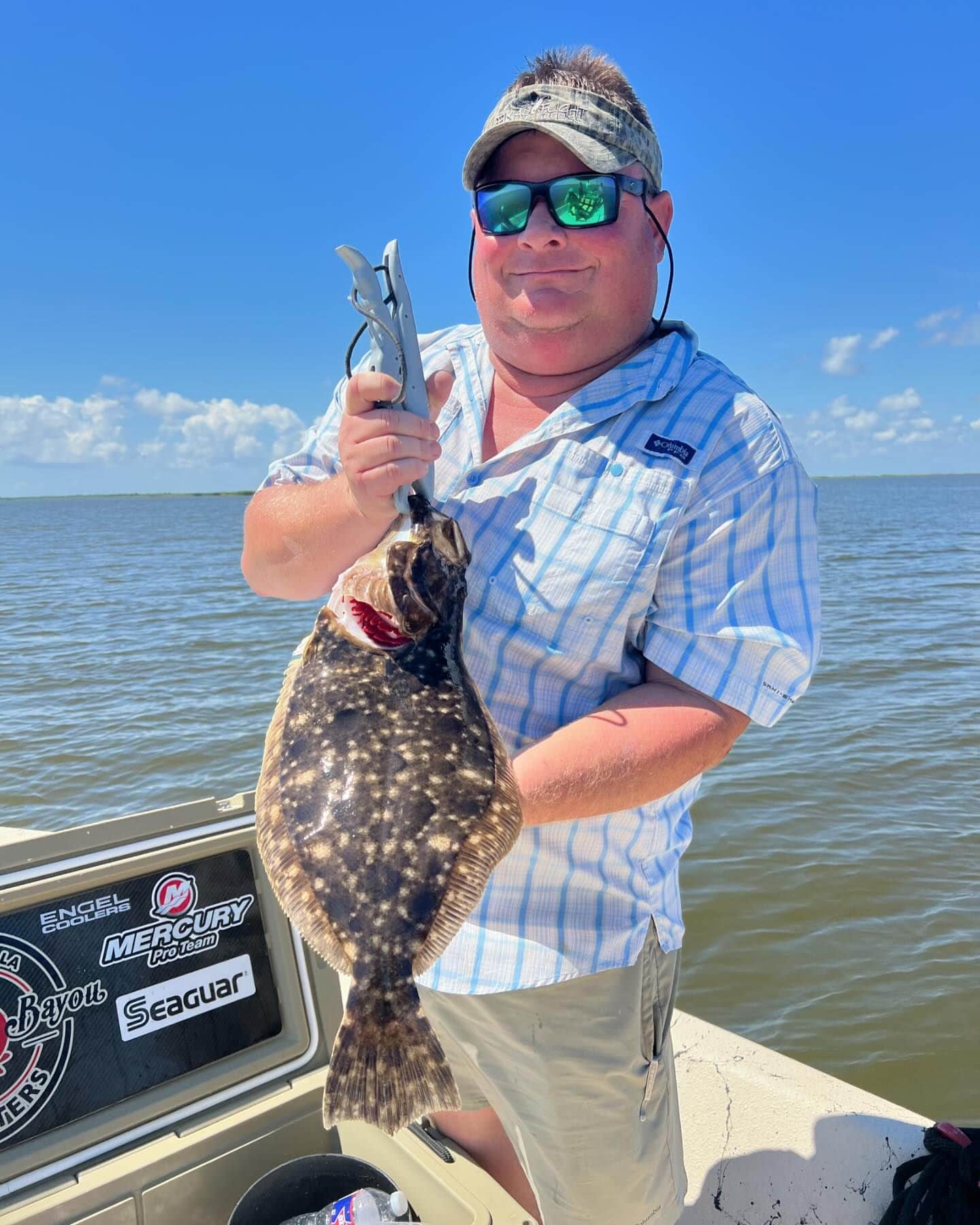 Man holding up a flounder he caught while fishing in Delacroix, LA with Whiskey Bayou Charters.