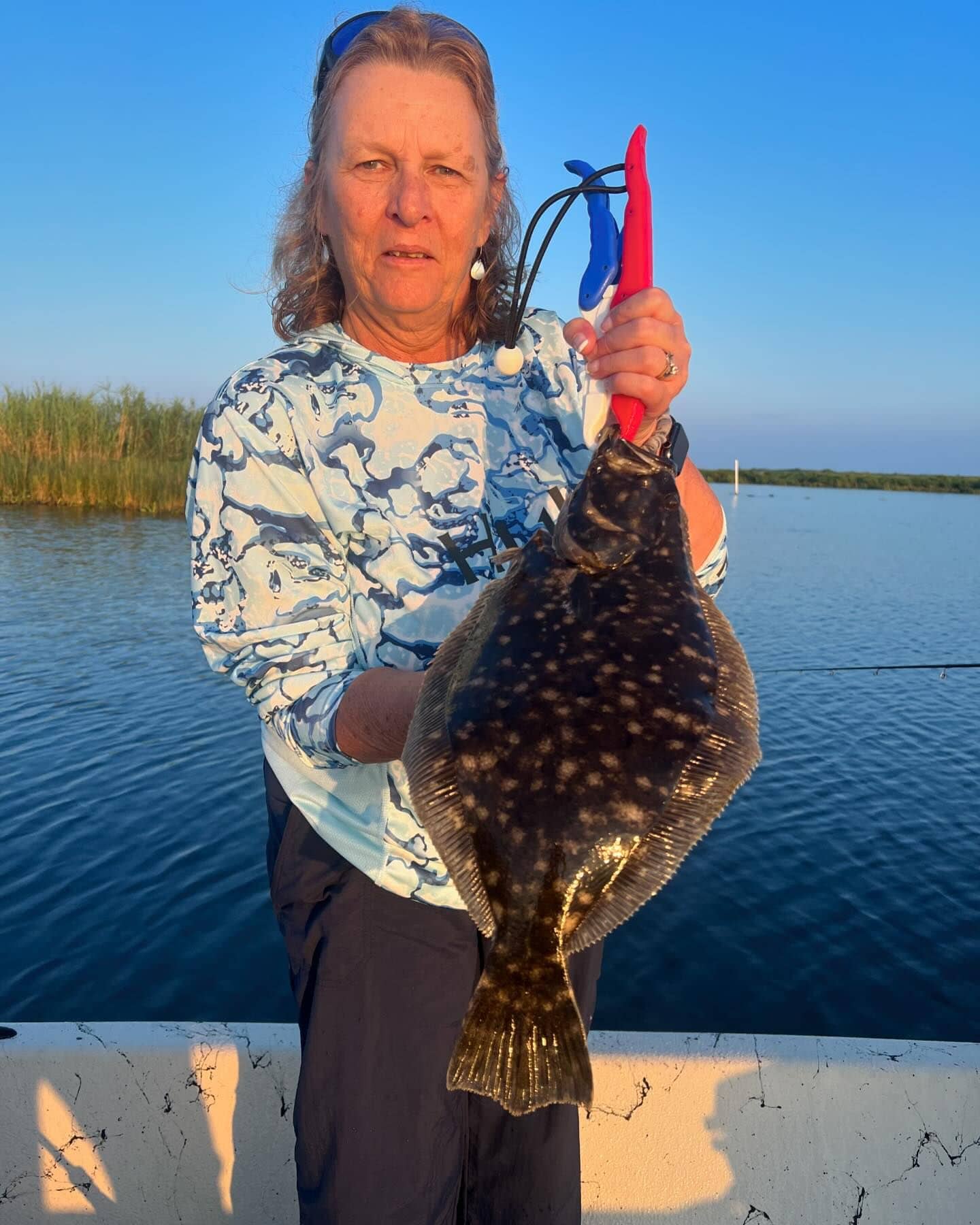 Woman holding up a flounder she caught while fishing with Whiskey Bayou Charters in Delacroix, LA.