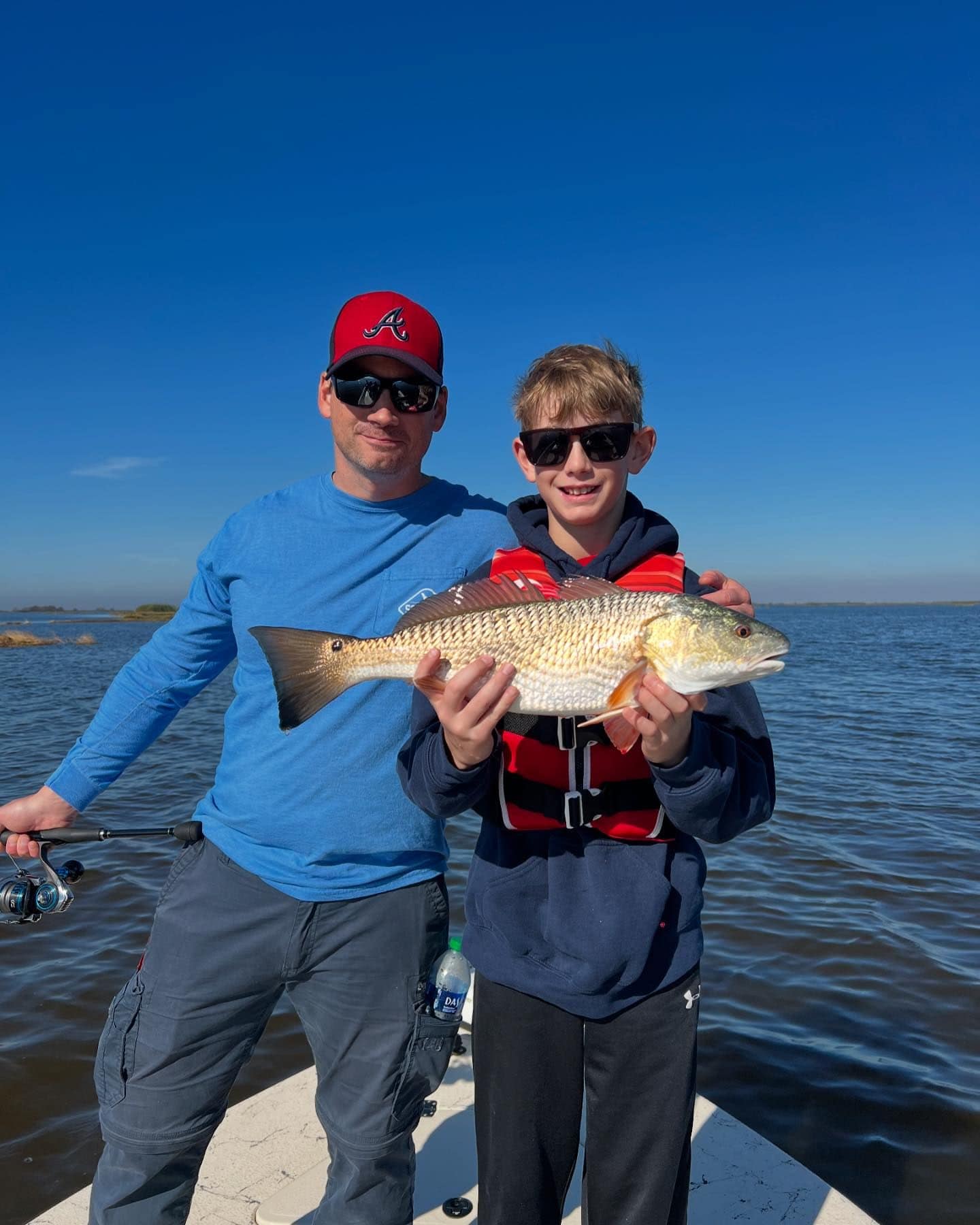 A father and son holding up a fish they caught while on a family-friendly fishing charter.