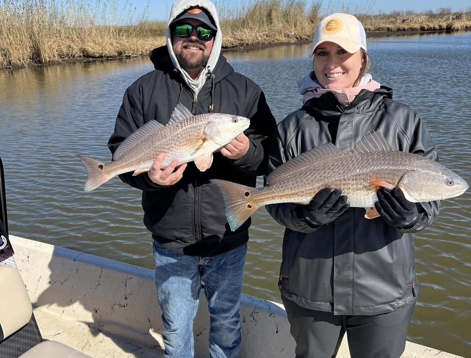 A couple holding up their catches for the camera